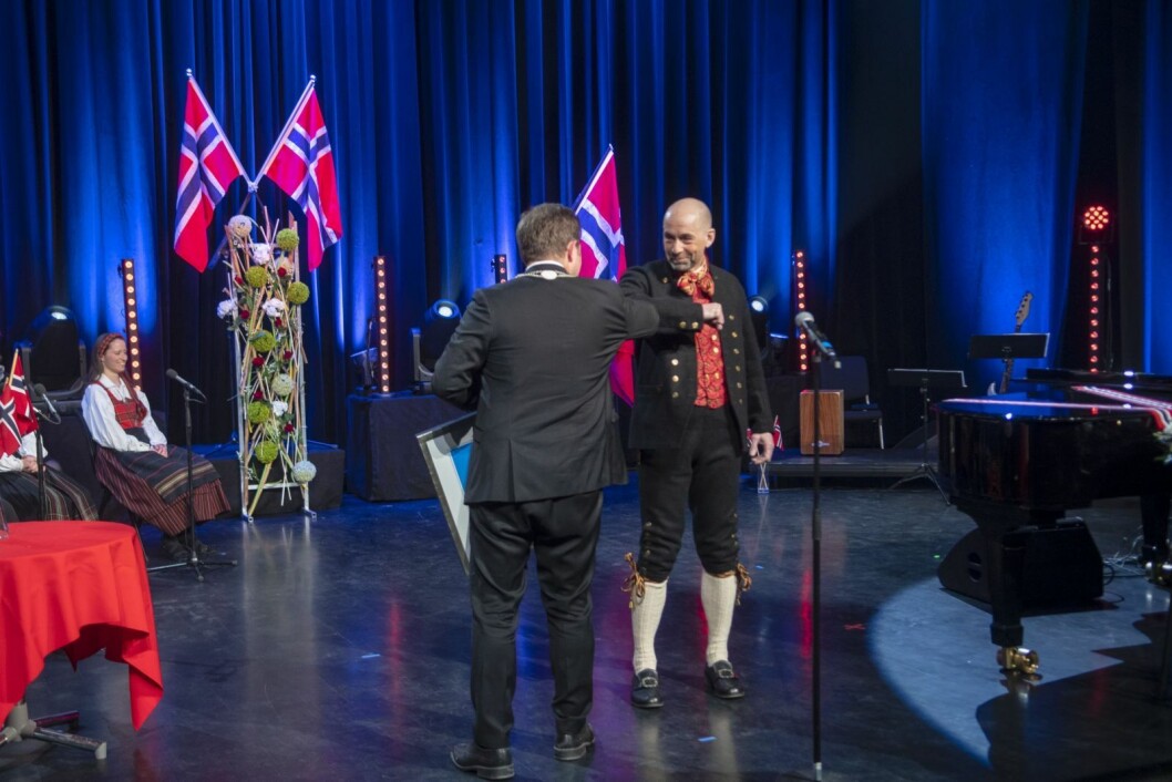 Fred Skancke Hansen får overrekt tyfusstatuetten av lokalstyreleder Arild Olsen med en koronahilsen. Fred Skancke Hansen får overrekt tyfusstatuetten av lokalstyreleder Arild Olsen med en koronahilsen.