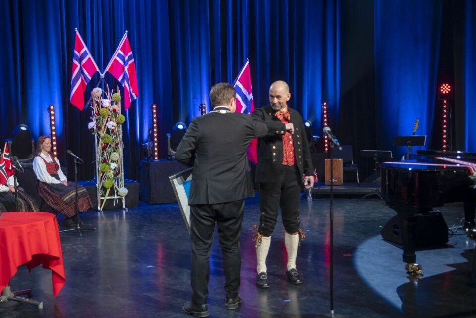 Fred Skancke Hansen får overrekt tyfusstatuetten av lokalstyreleder Arild Olsen med en koronahilsen.