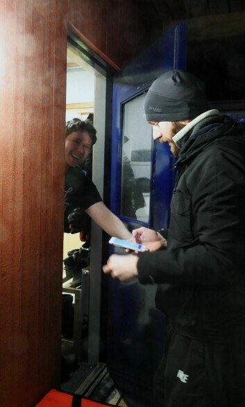 Kveldens første kunde, Tor Kristian Tønnesen, smiler fra øre til øre når han åpner døren til rykende fersk hjemmelevering fra Svalbard Delivery Service.