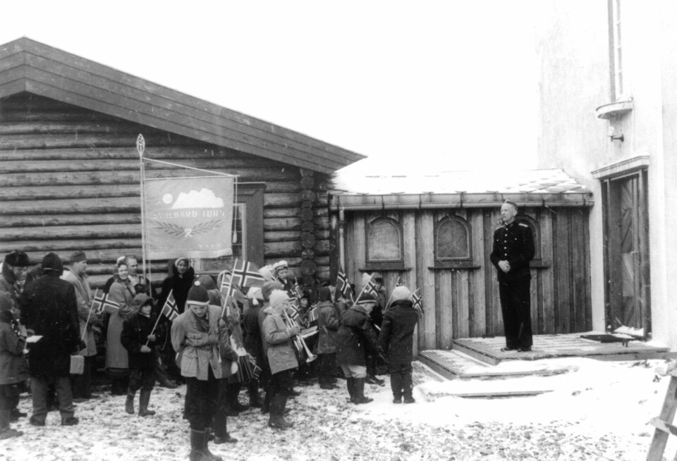Feirende barn og voksne hører sysselmannen tale. Bildet er tatt i sysselmannsgården på slutten av 1950-tallet. Feirende barn og voksne hører sysselmannen tale. Bildet er tatt i sysselmannsgården på slutten av 1950-tallet.