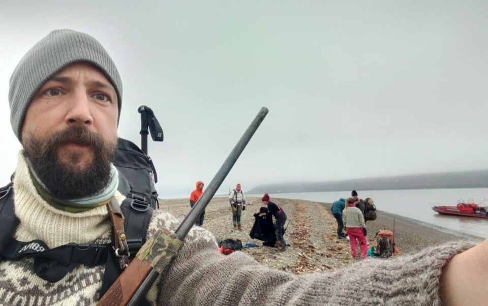 Skrottestudiar på Svalbard: Prosjektleiar Sam Steyaert med felt-teamet i bakgrunnen. Bilete er tatt i Hiorthhamn medan dei ventar på båtskyss attende til Longyearbyen etter end arbeidsdag.