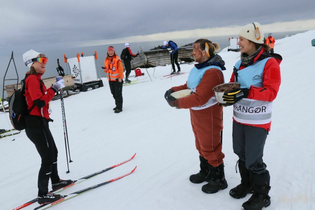 DELER UT: Mona Dahl (i apedrakt) og Ida Johannessen (t.h.) deler ut banan og sjokolade på matstasjonen etter 12 km. Svalbard skimaraton 2019.