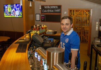 Bartender Taivo Miilmaa, her iført Estland-drakt, trives godt med å ha fotballkamper i bakgrunnen når han jobber. 