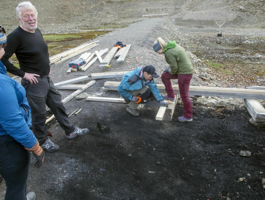 Anders Magne Lindseth (t.v.) trommet ihop en gjeng med folk fra Longyearbyen jeger- og fiskerforening for å reparerere skytebanen etter brannen i helga. På bildet sager Øystein Mønster og Hilde Antonsen.