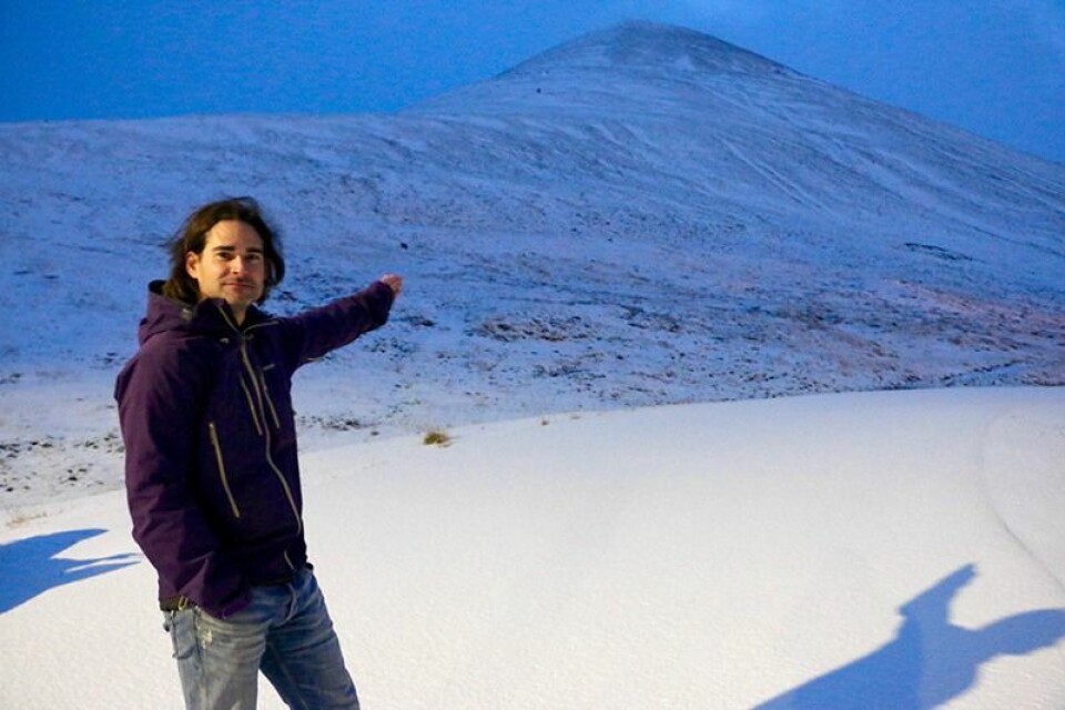 Alexander Prokop peker mot området der 11 hus ble ødelagt av skred. Sterk vind deponerte inntil 4 meter snø i bakkene bak Prokop. Alle rester av de ødelagte husene er blitt fjernet.