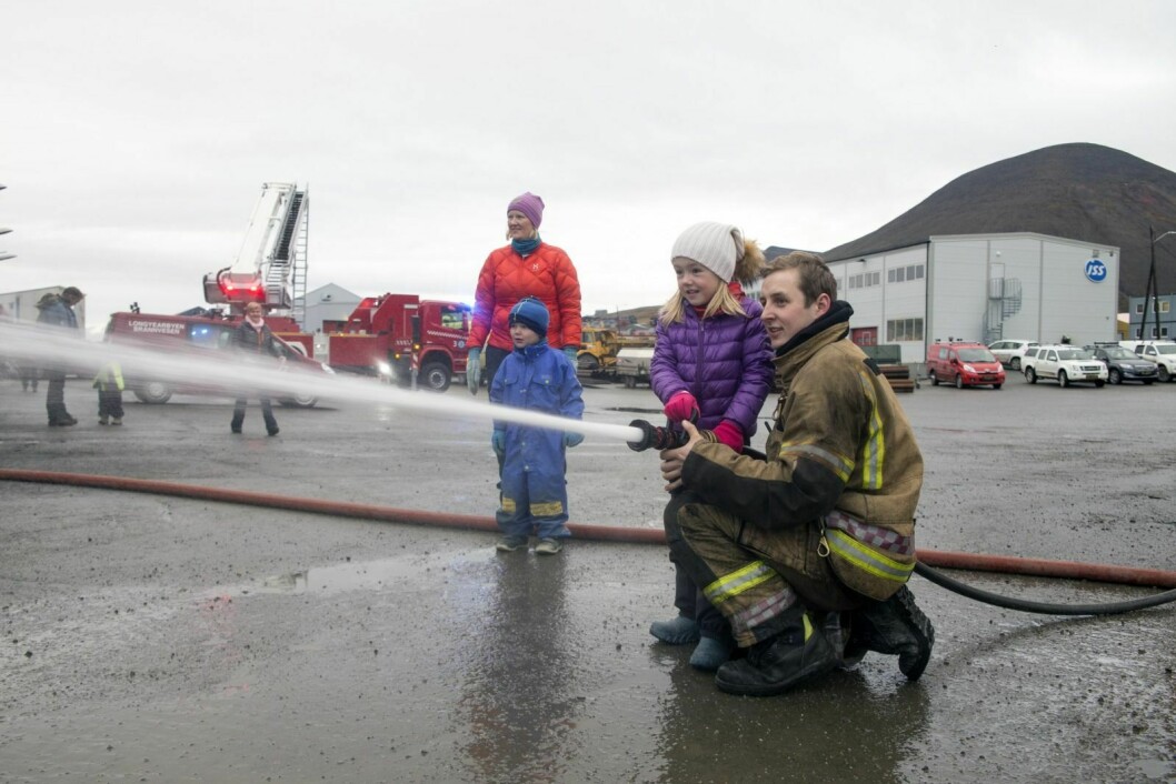 Åpen dag på brannstasjonen i Longyearbyen. Eva Helen Hultgren (6) får instruksjon i bruk av brannslange av brannmann Odd Rune Svenning. Bak står Hege Leithe og sønnen Elias (3) og ser på.