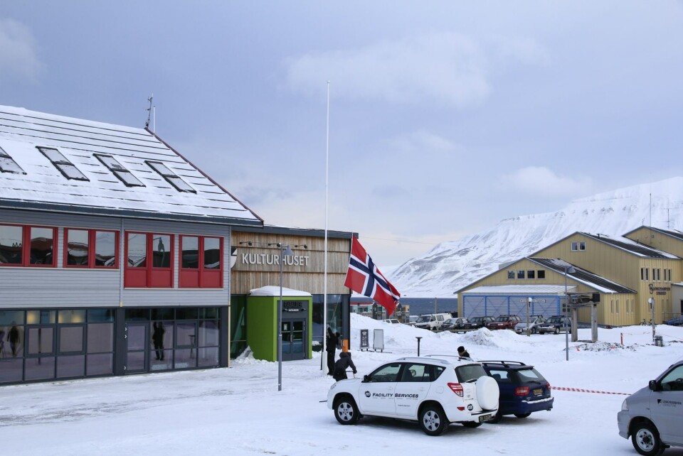 Vaktmester Isa Iljasov i Longyearbyen lokalstyre heiser flagget for dronningbesøket torsdag morgen.