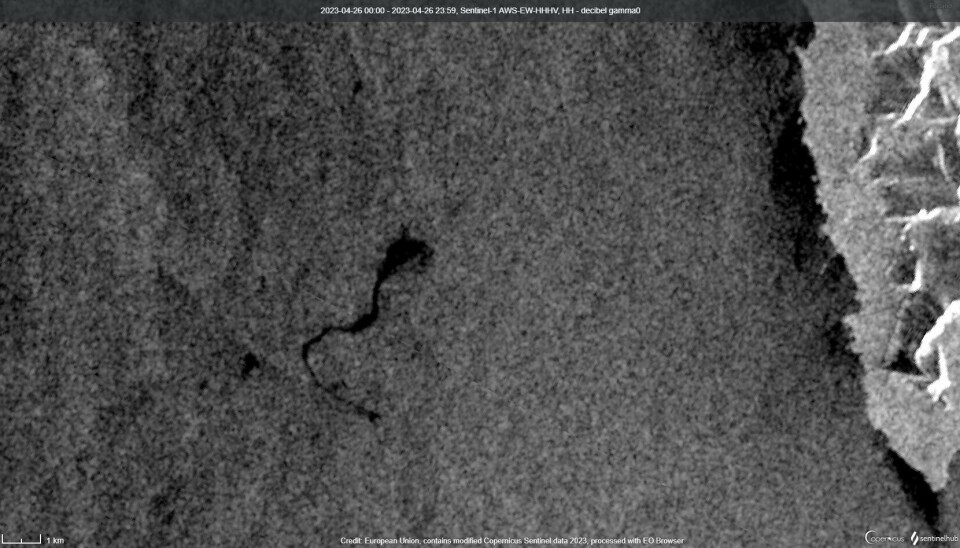 Bildet, som er tatt med satellitten Sentinel-1, viser havflaten utenfor Prins Karls Forland 26. april 2023. Et svart oljeflak er rett til venstre for midten av bildet. Flaket er 8 kilometer langt og dekker rundt 2,4 kvadratkilometer. Prins Karls Forland ligger til høyre på bildet (lysere gråtoner og hvitt).