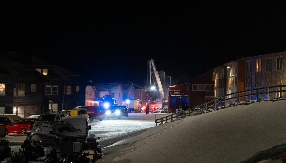 Brannbiler både fra Longyearbyen brannvesen og Avinor er på stedet. Det gule bygget kalt «Lang trang gang» til høyre i bildet har vært evakuert. Nå kan folk flytte tilbake.